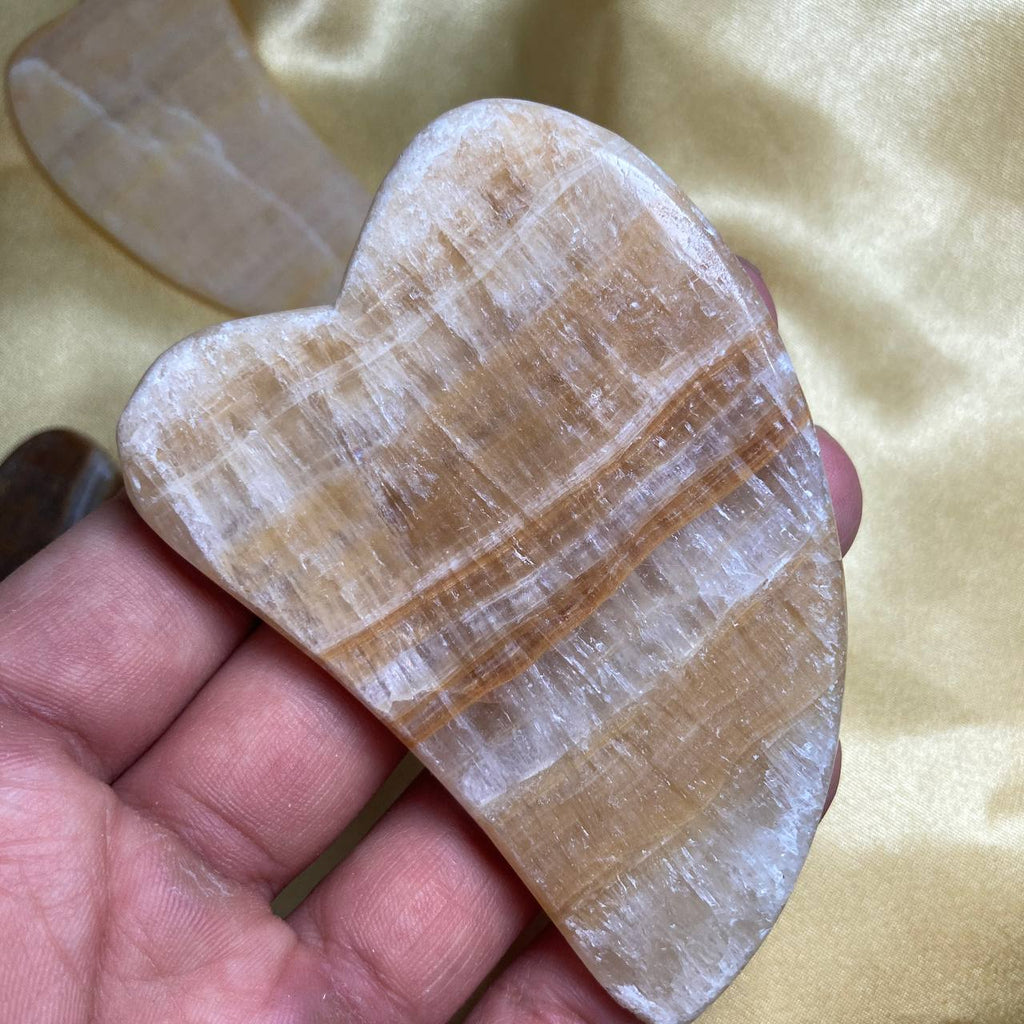 Heart-shaped stone held in a hand against a yellow fabric background