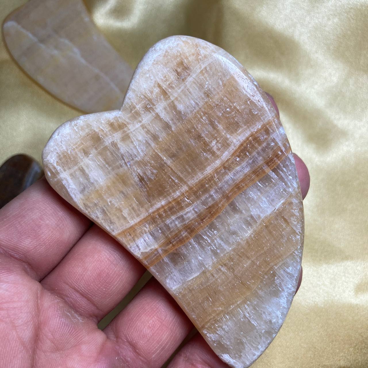 Heart-shaped stone held in a hand against a yellow fabric background