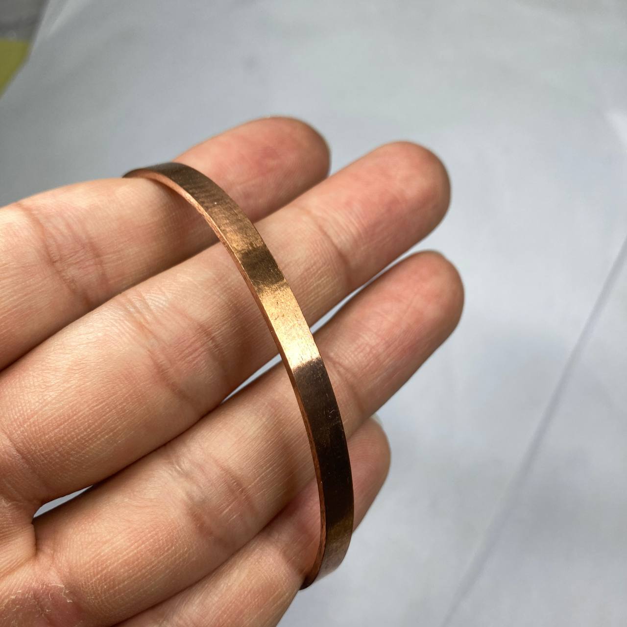 Copper bracelet on a person's wrist against a white background
