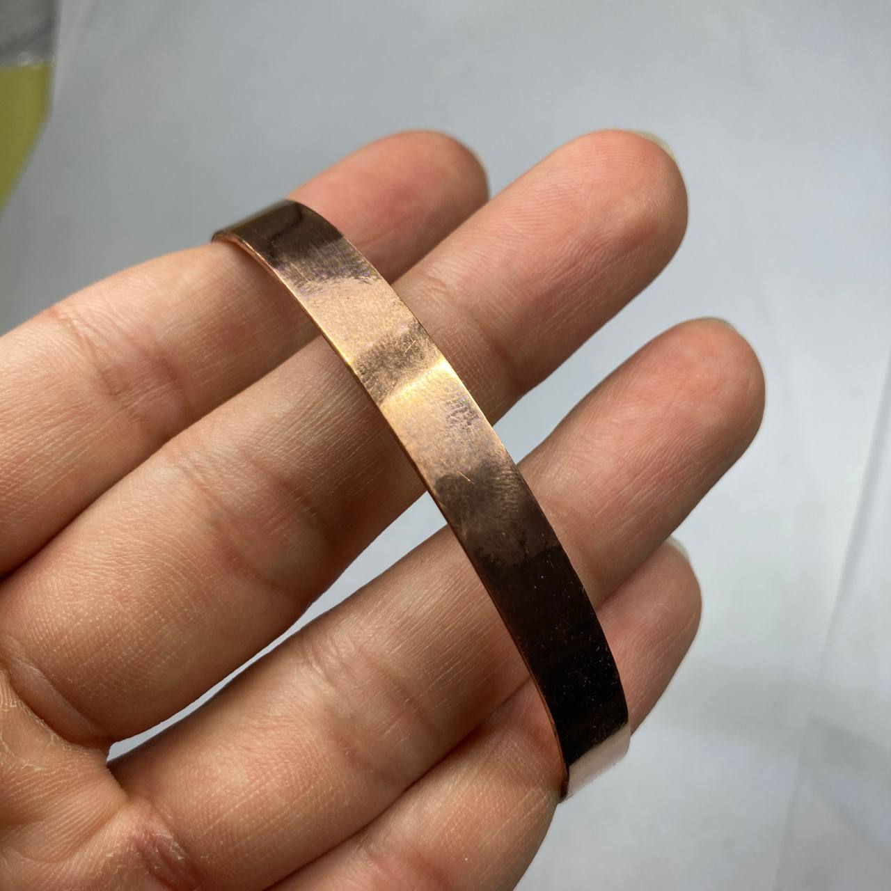 Rose gold ring on a person's finger against a white background