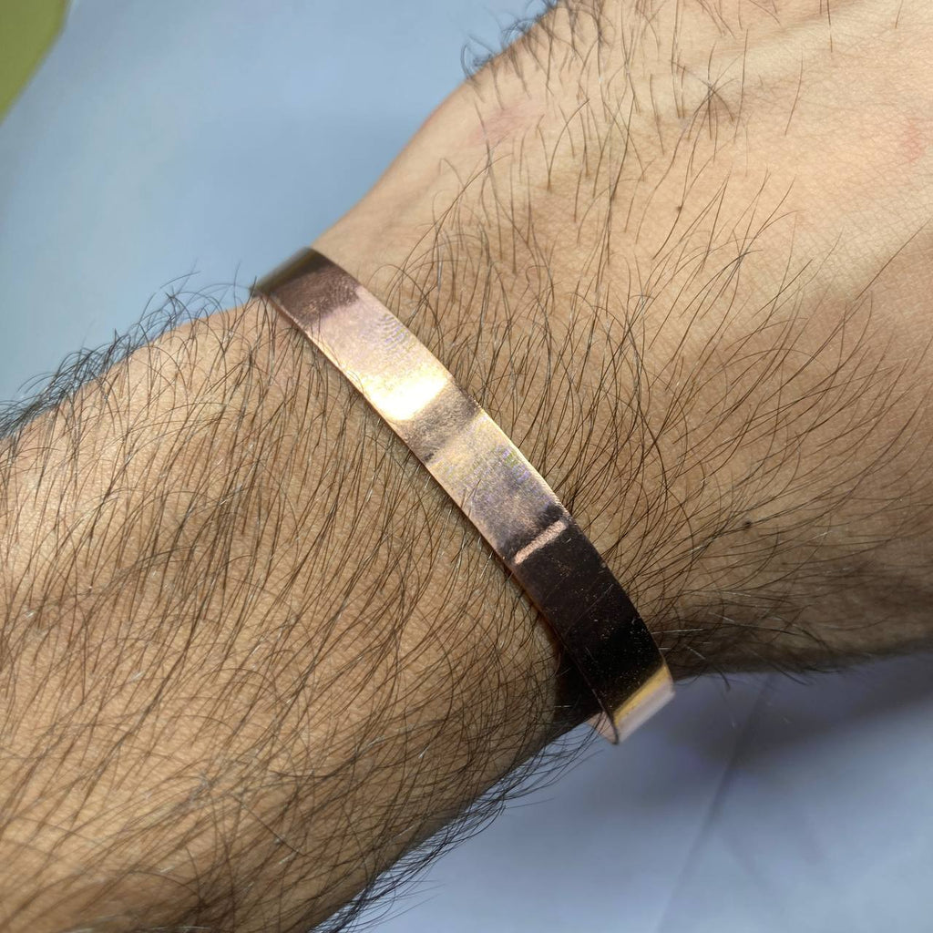 Gold bracelet on a wrist with a light blue background
