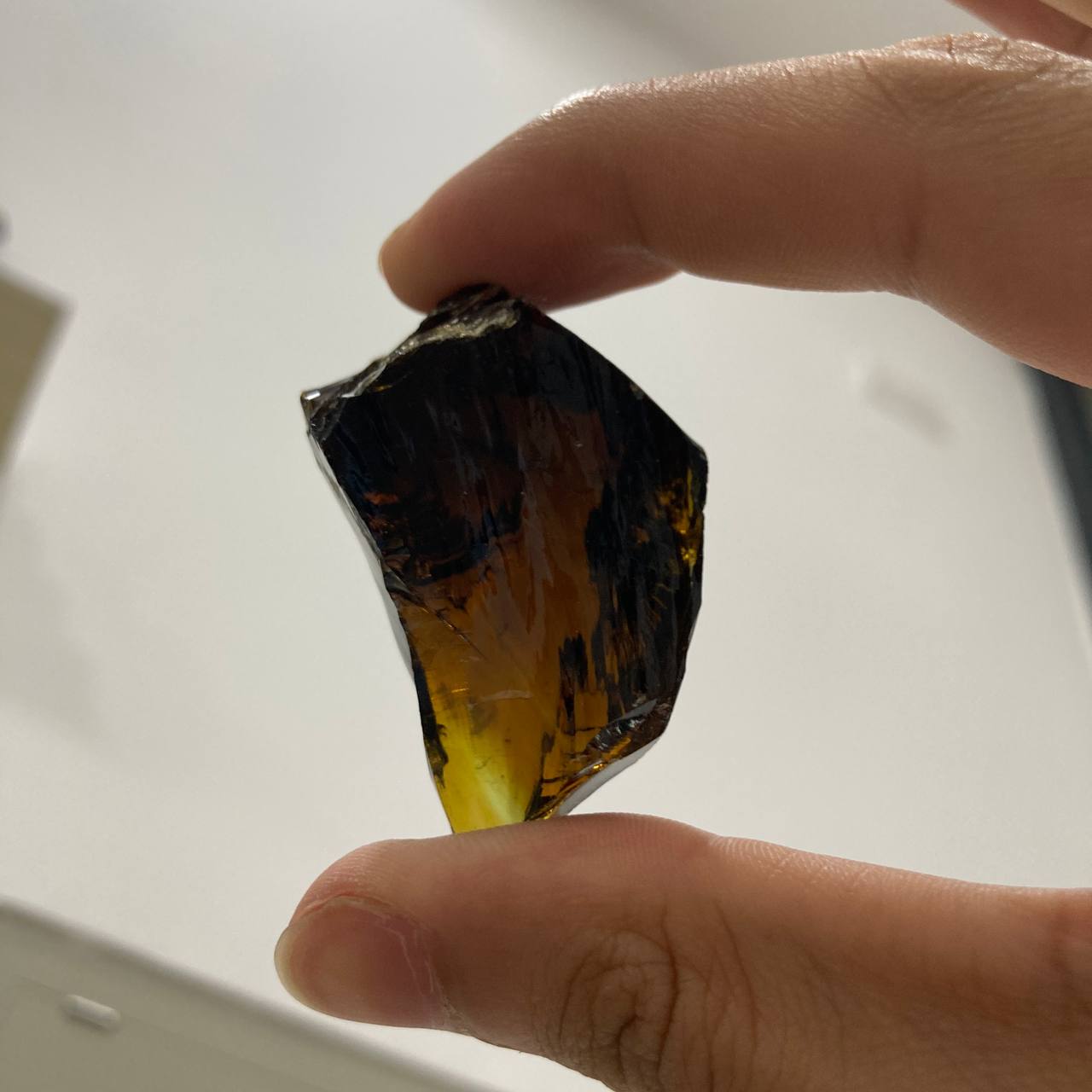 Hand holding a rough crystal rock against a neutral background