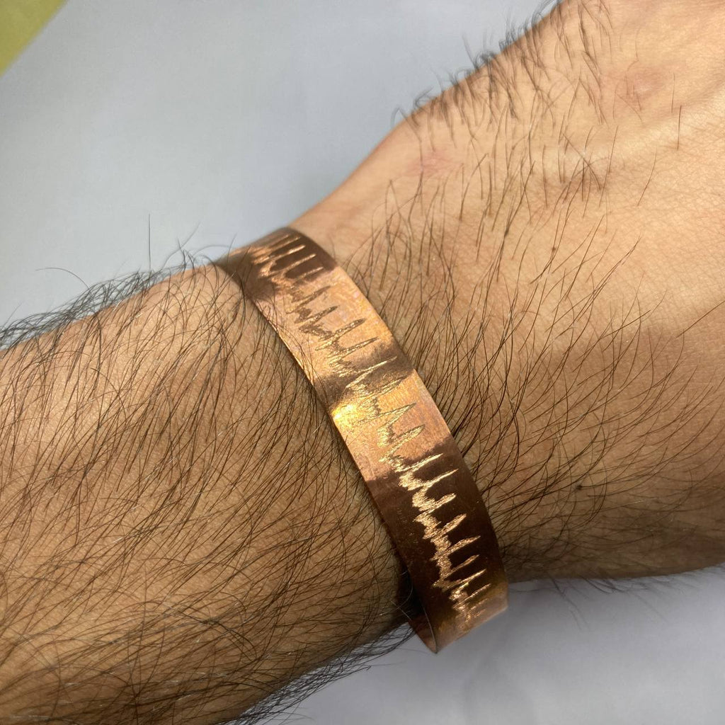 Copper bracelet on a wrist with a textured design