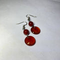 Pair of red circular earrings on a white background