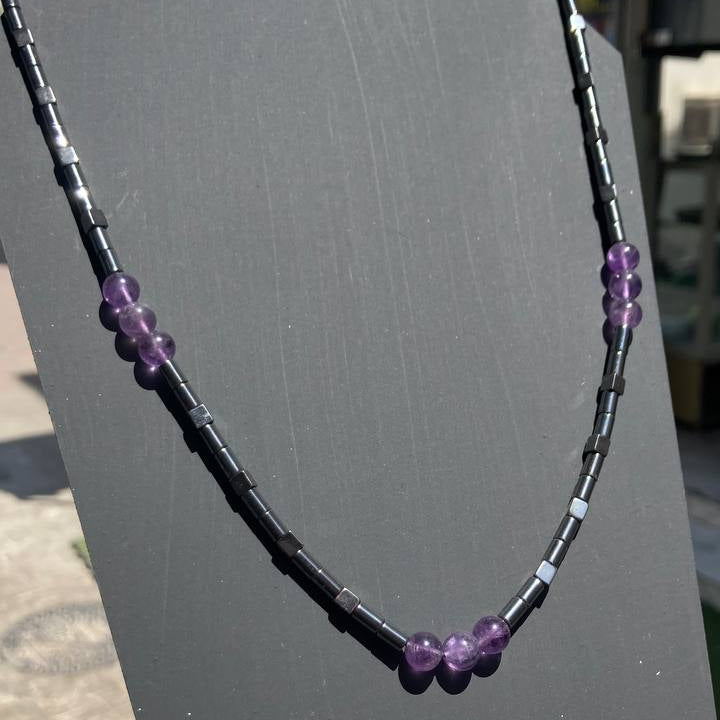 Necklace with purple beads on a gray surface 