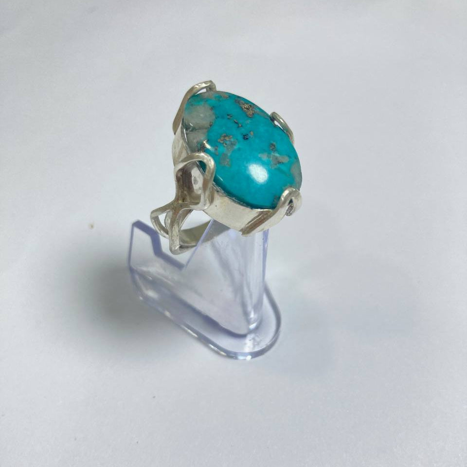 Turquoise ring on a clear stand against a white background