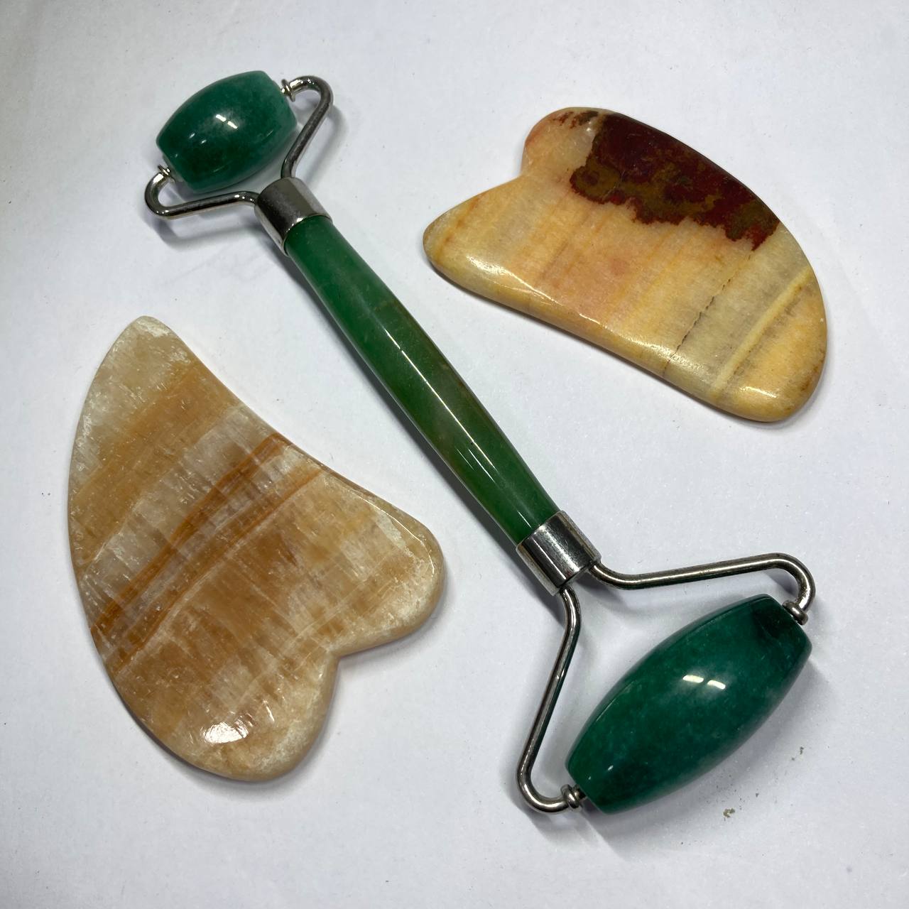 Green roller tool with two stone tools on a white background