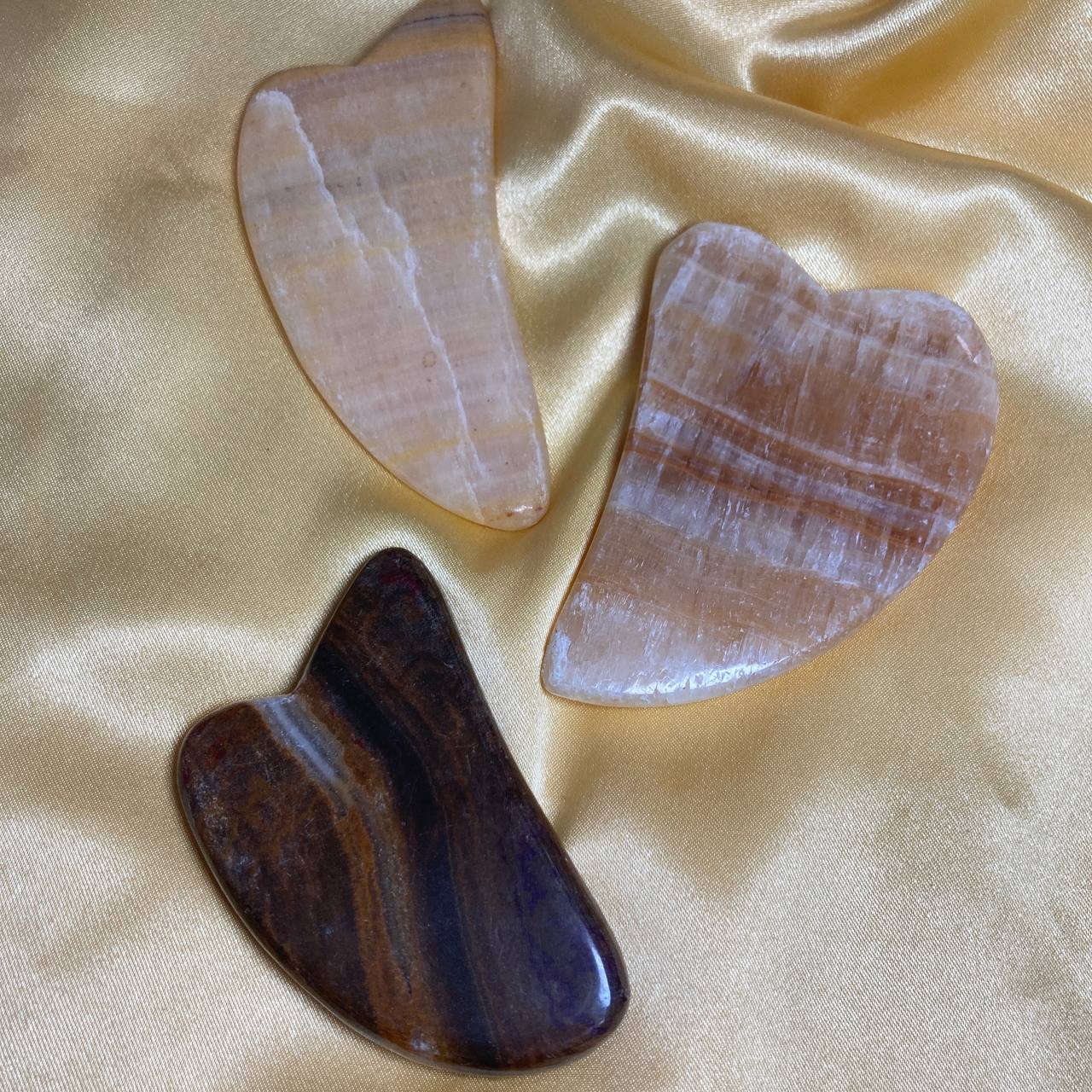 Three stone tools on a satin surface