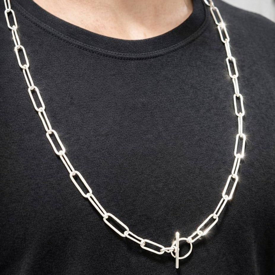 Person wearing a silver chain necklace on a black shirt