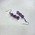 Purple beaded earrings on a white background
