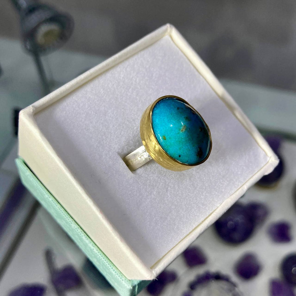 Gold ring with a blue stone in a box on a blurred background