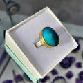 Gold ring with a blue stone in a box on a blurred background