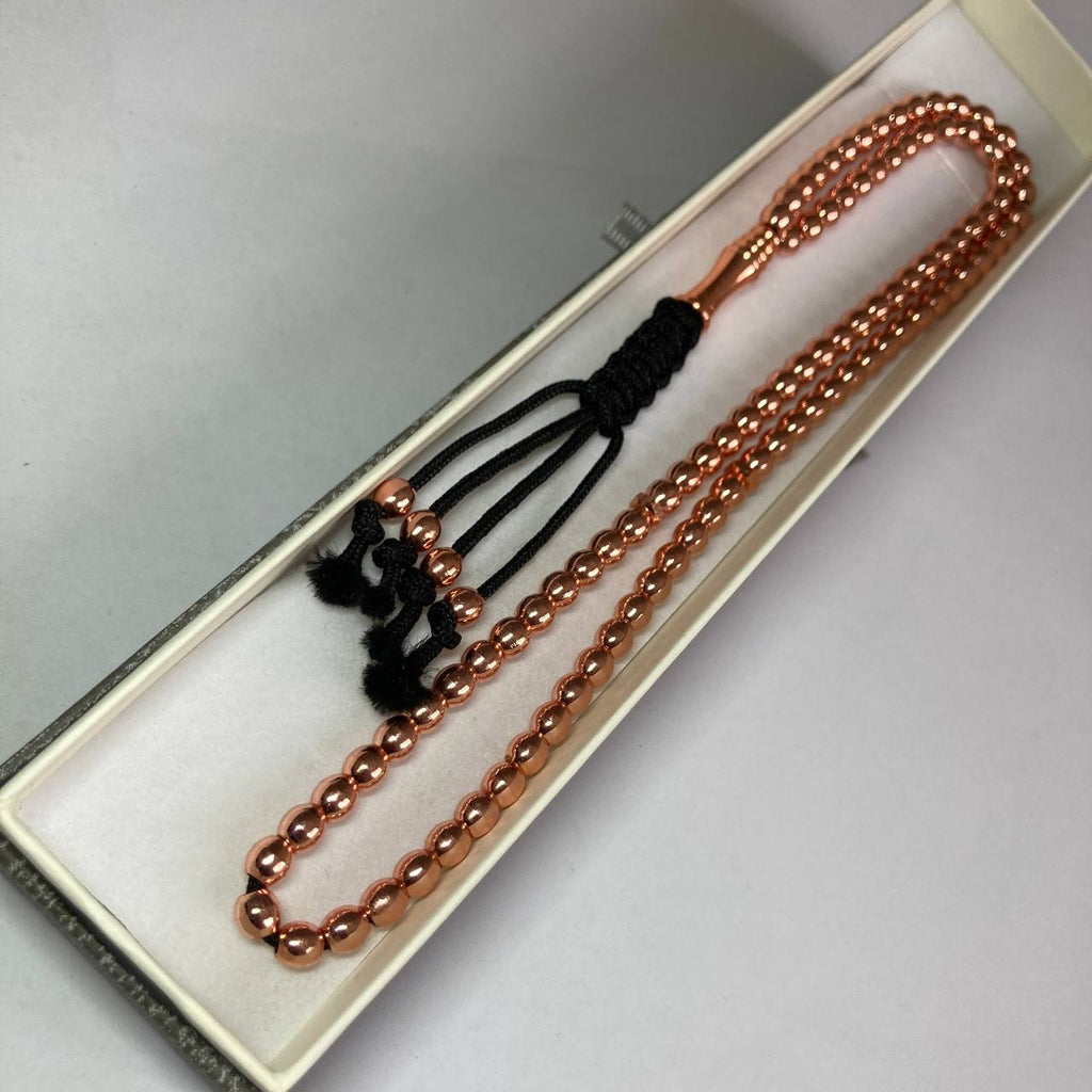 Rose gold beaded necklace with black cord tassels, displayed inside a cream-colored presentation box.