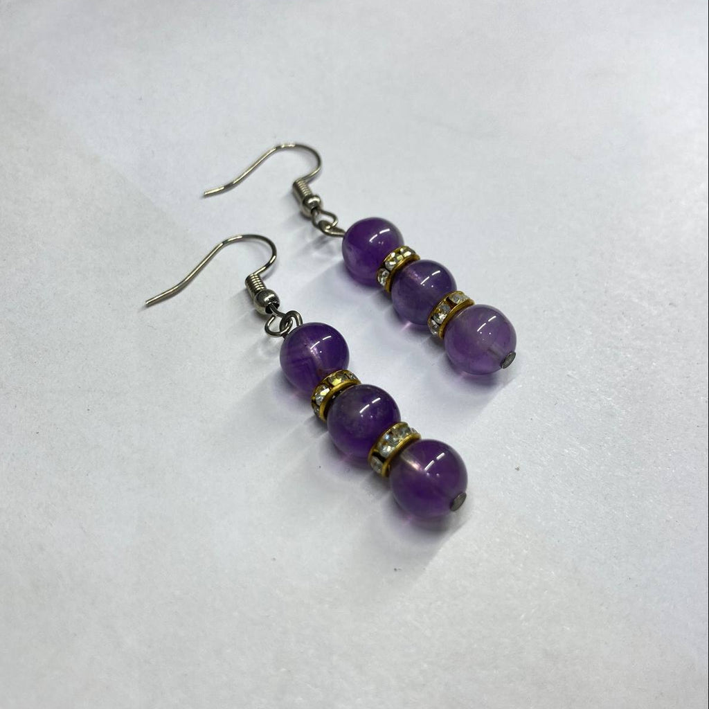 Pair of purple beaded earrings on a white background