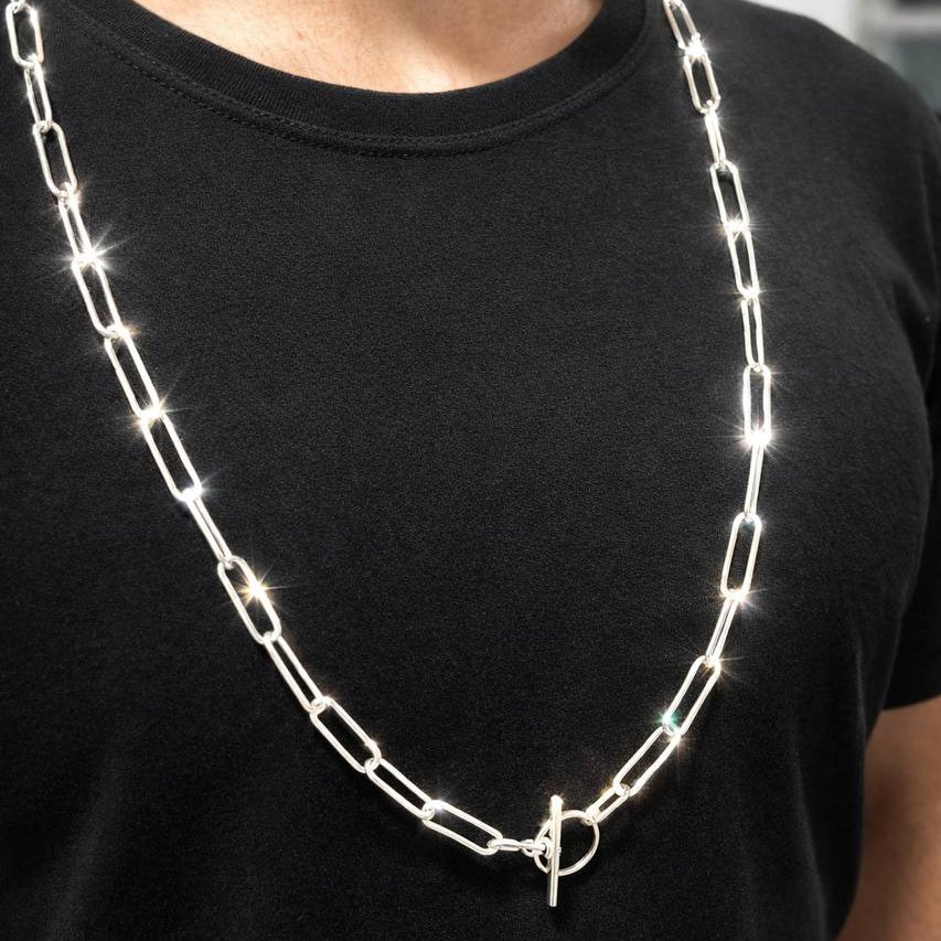 Person wearing a black t-shirt with a silver chain necklace.