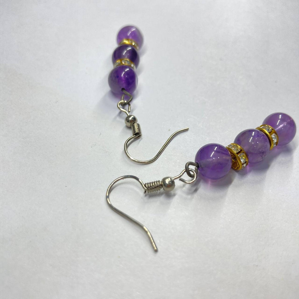 Purple beaded earrings with golde accents on a white background