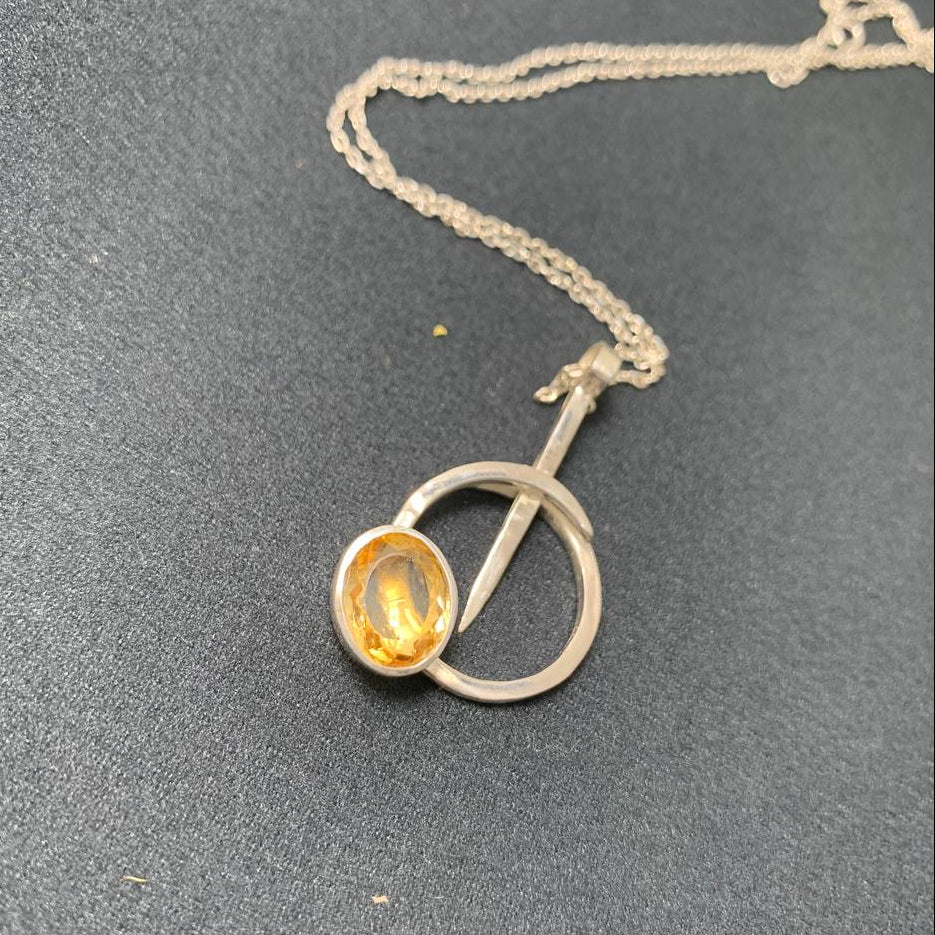 Silver necklace with a round pendant on a gray surface