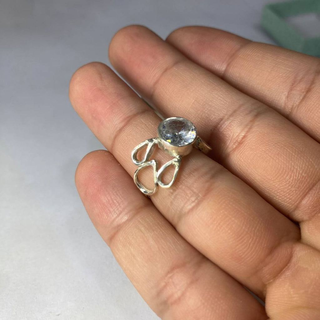 Silver ring with a clear gemstone on a hand against a light background