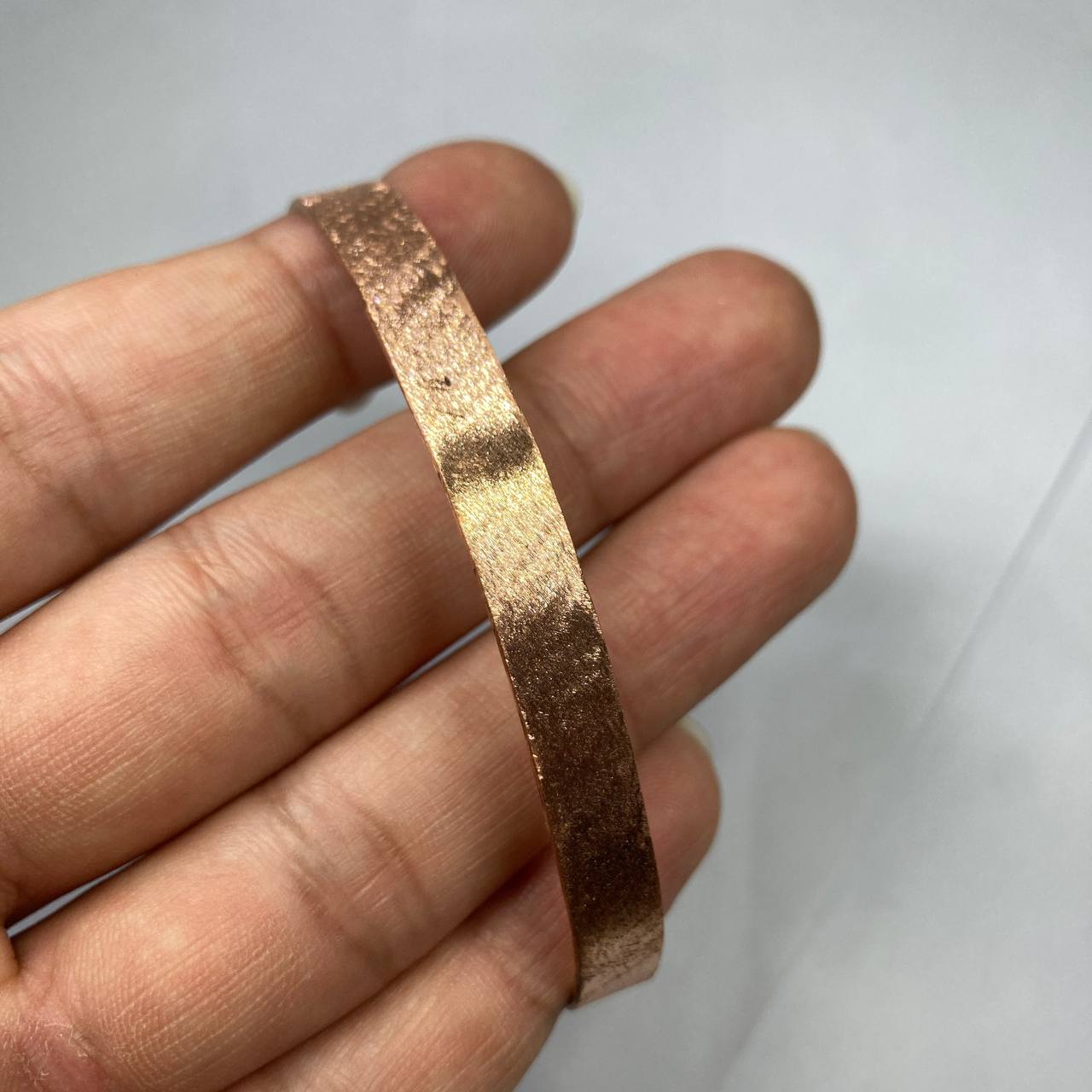 Rose gold bracelet on a person's wrist against a white background