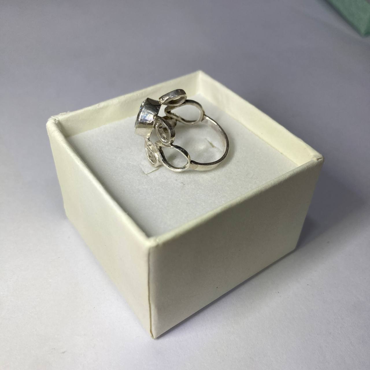 Silver ring in a white jewelry box on a gray background
