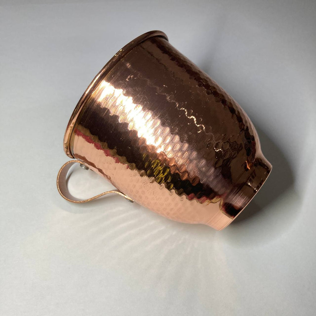 A hammered copper mug with a matching copper handle, shown on a light gray background.