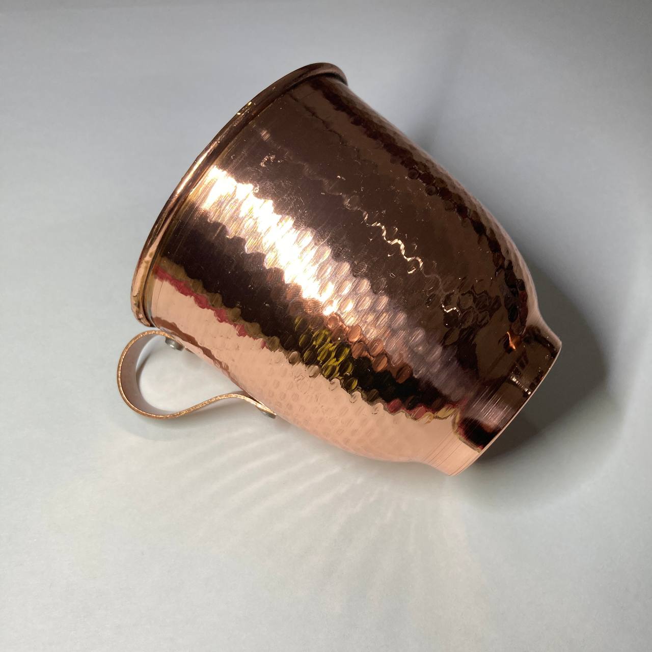 A hammered copper mug with a matching copper handle, shown on a light gray background.