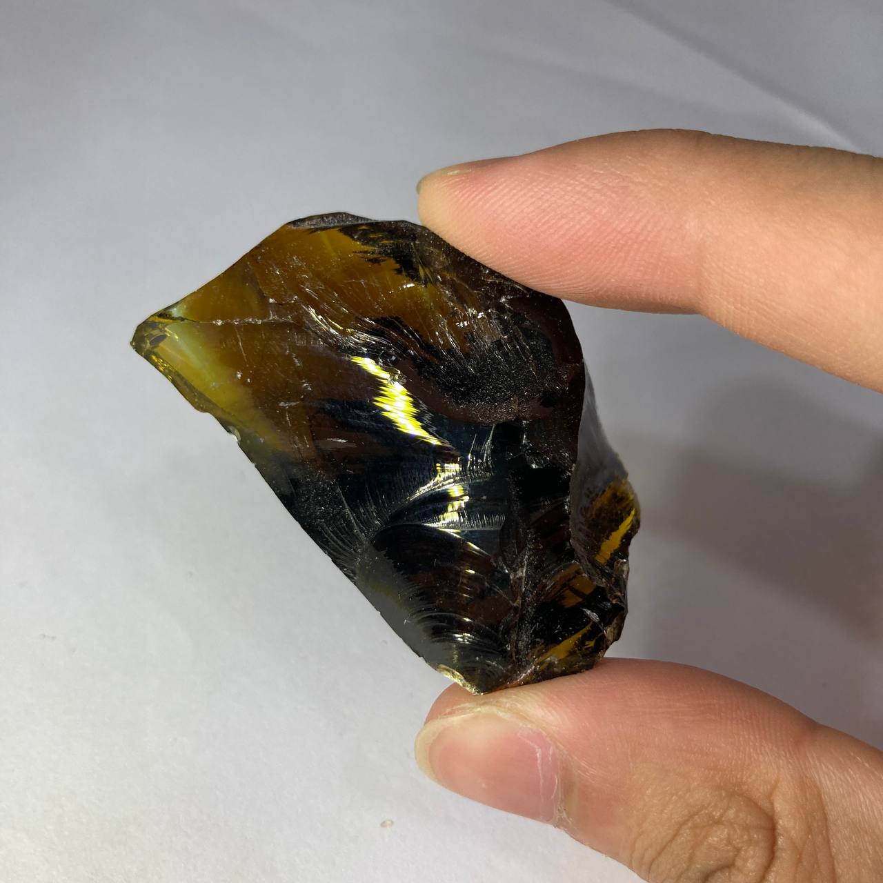 Hand holding a rough crystal rock on a white background