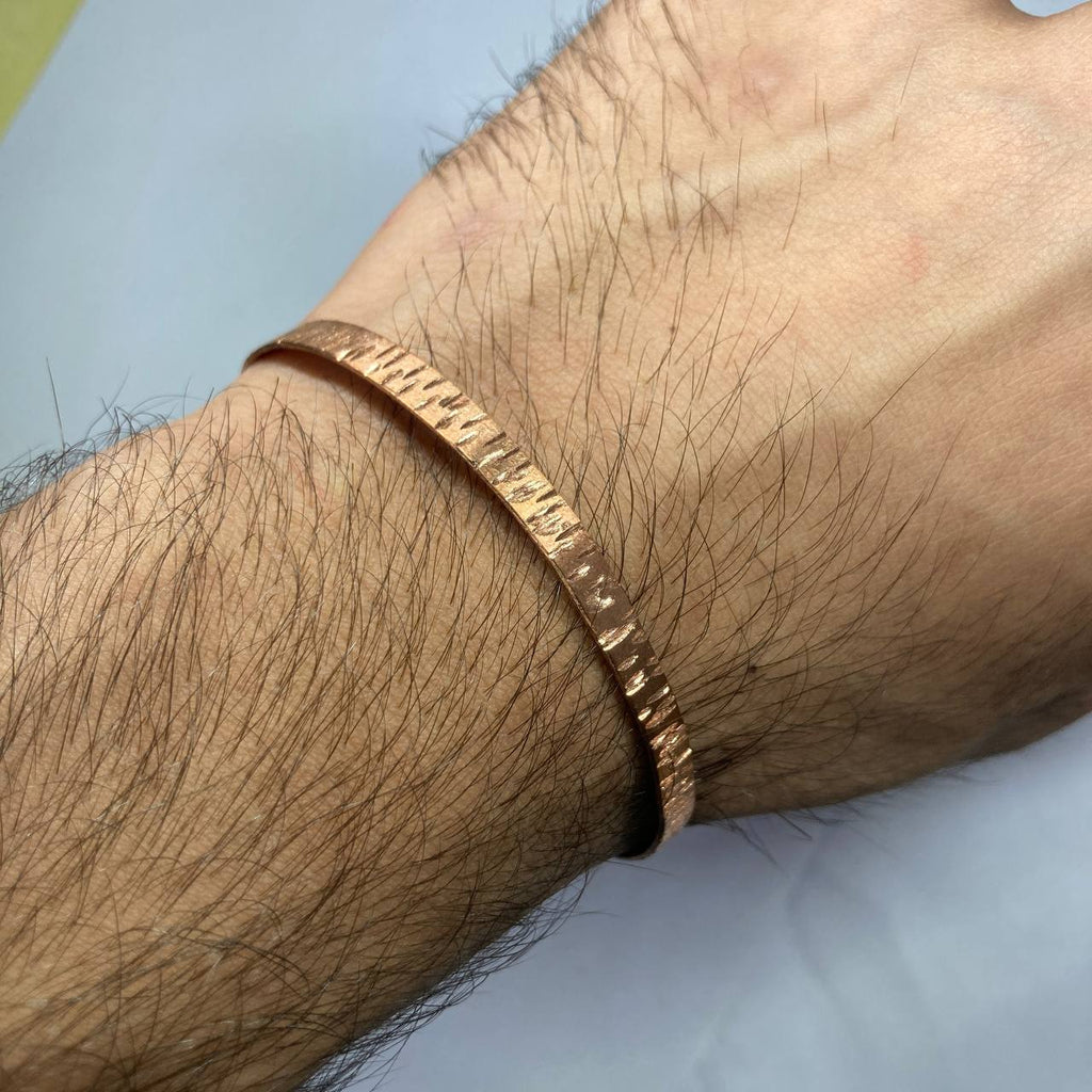 Close-up of a copper bracelet on a wrist with a light background
