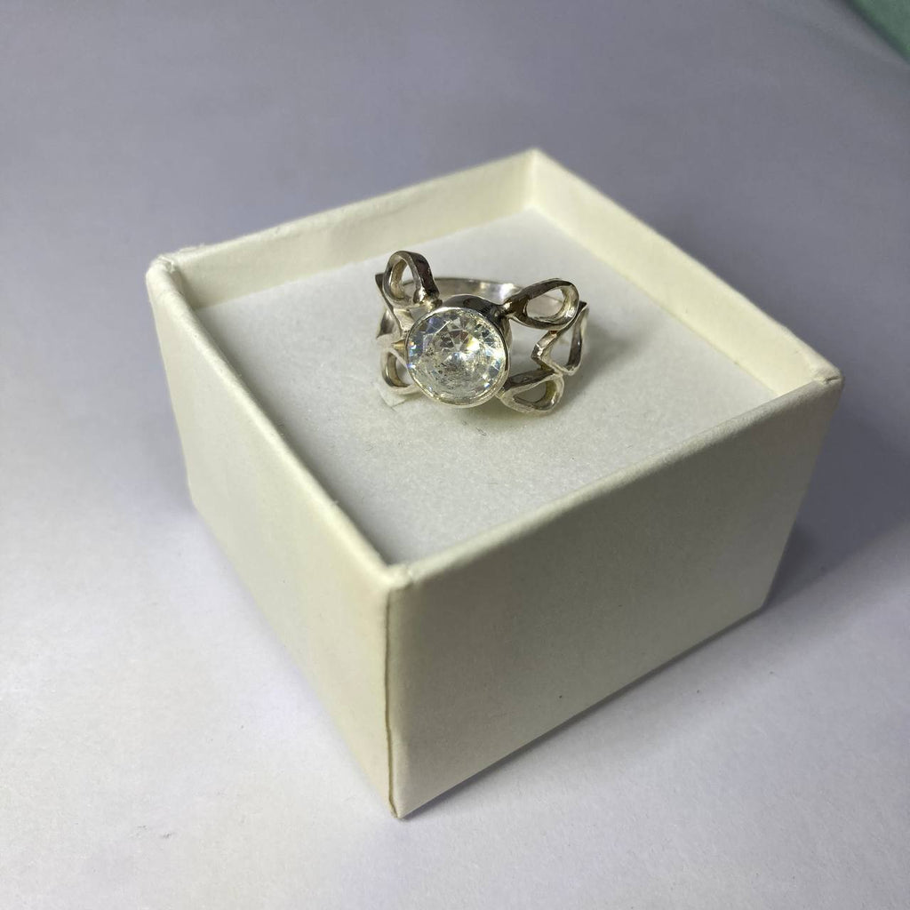 Silver ring with a large gemstone in a white box on a gray background