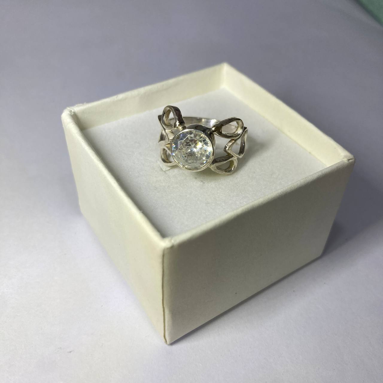 Silver ring with a large gemstone in a white box on a gray background