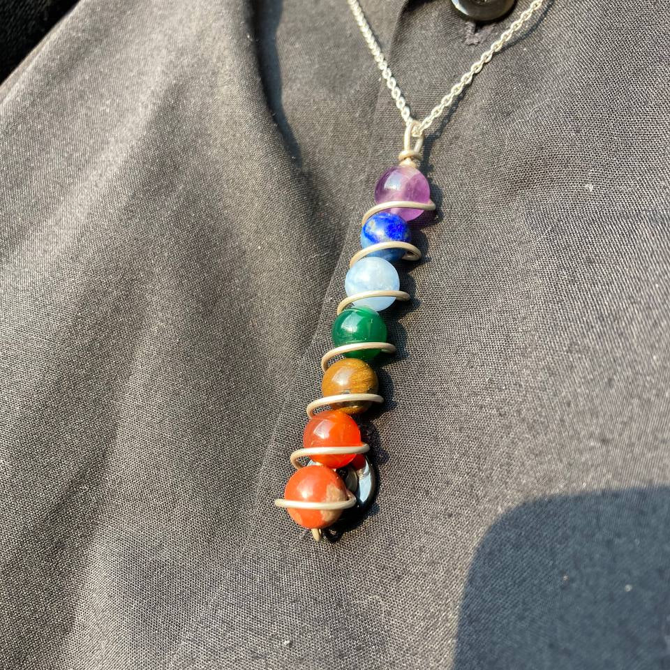 Necklace with chakra beads on a gray fabric background