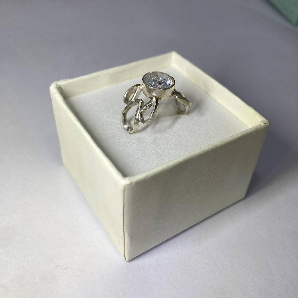 Silver ring with a gemstone in a white box on a gray background
