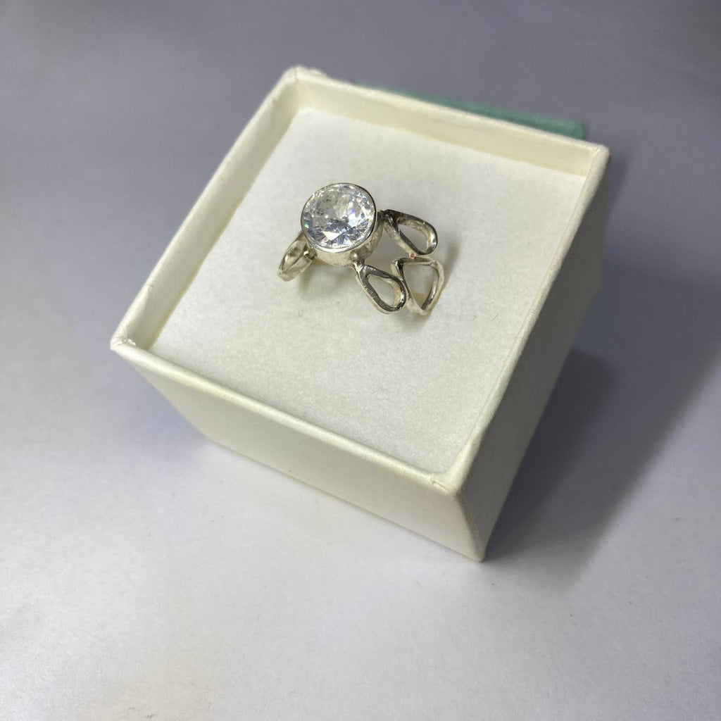 Silver ring with a large gemstone in a white box on a gray background