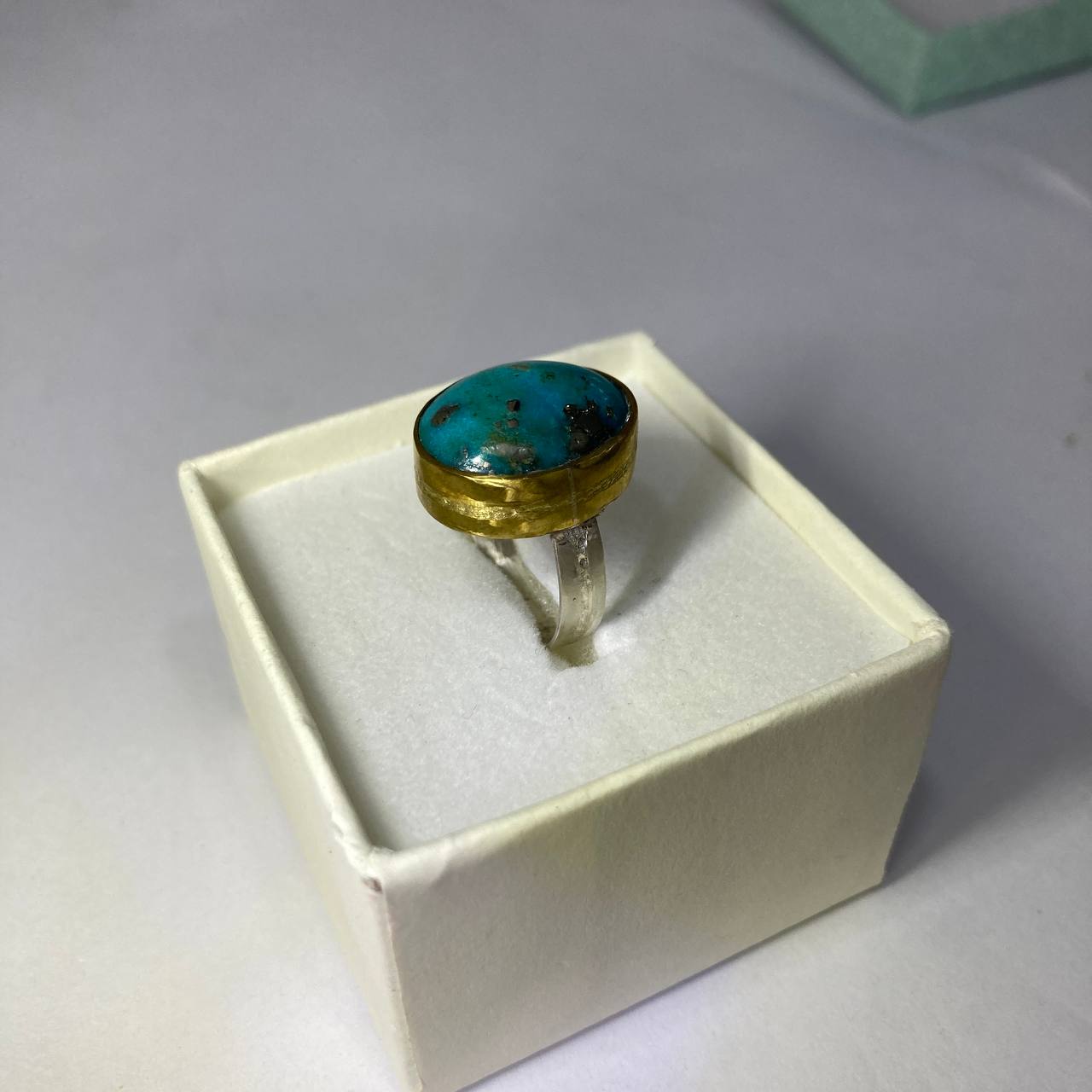 silver-brass ring with a turquoise stone in a jewellry box on a neutral background