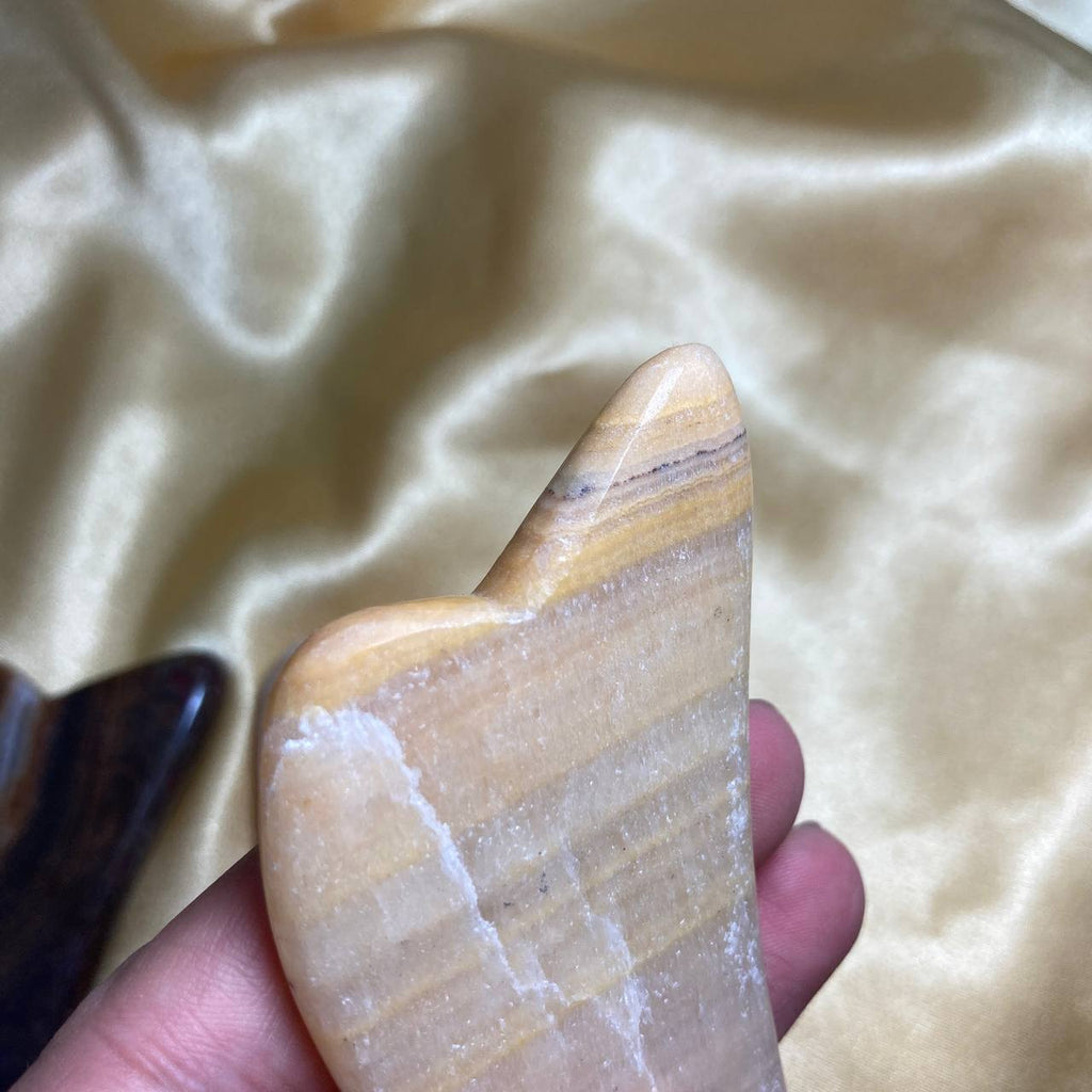 Hand holding a stone with striped pattern against a beige fabric background