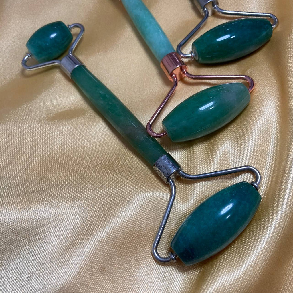 Two jade rollers on a beige fabric background