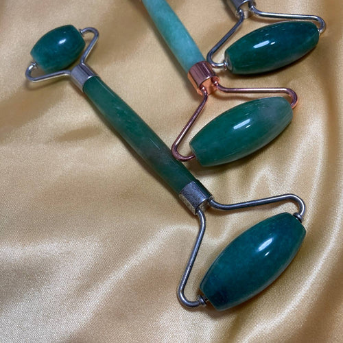 Two jade rollers on a beige fabric background