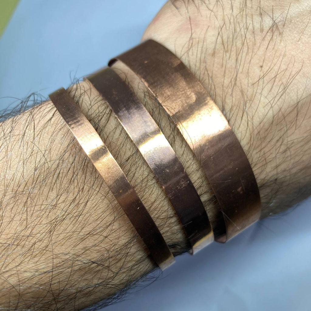Close-up of a person's wrist wearing a copper bracelet on a light blue background