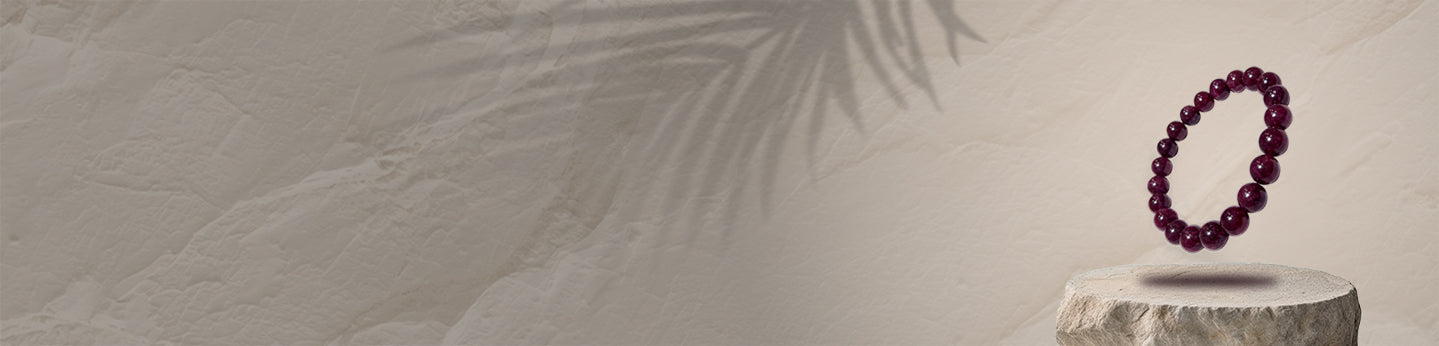 Red garnet beaded bracelet on a wooden pedestal with a textured beige background