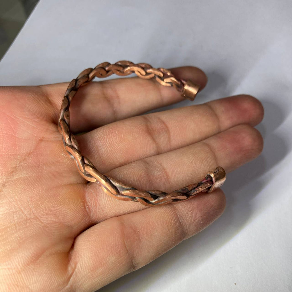 Copper bracelet on a hand against a white background