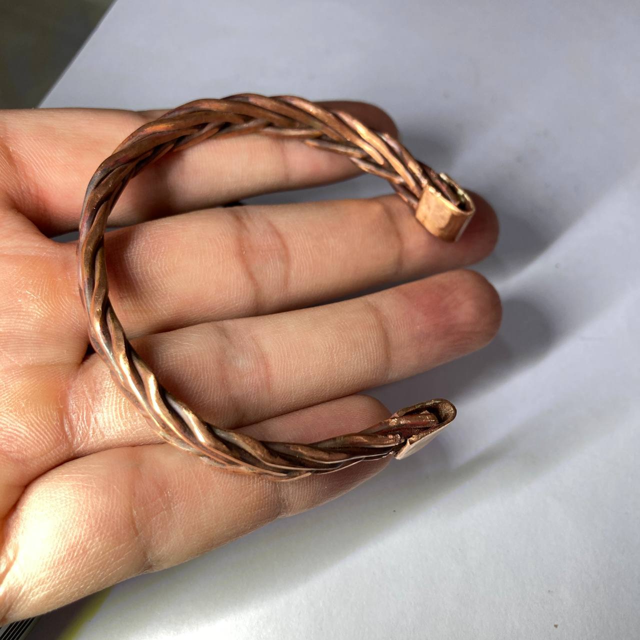 Copper bracelet on a hand with a light background