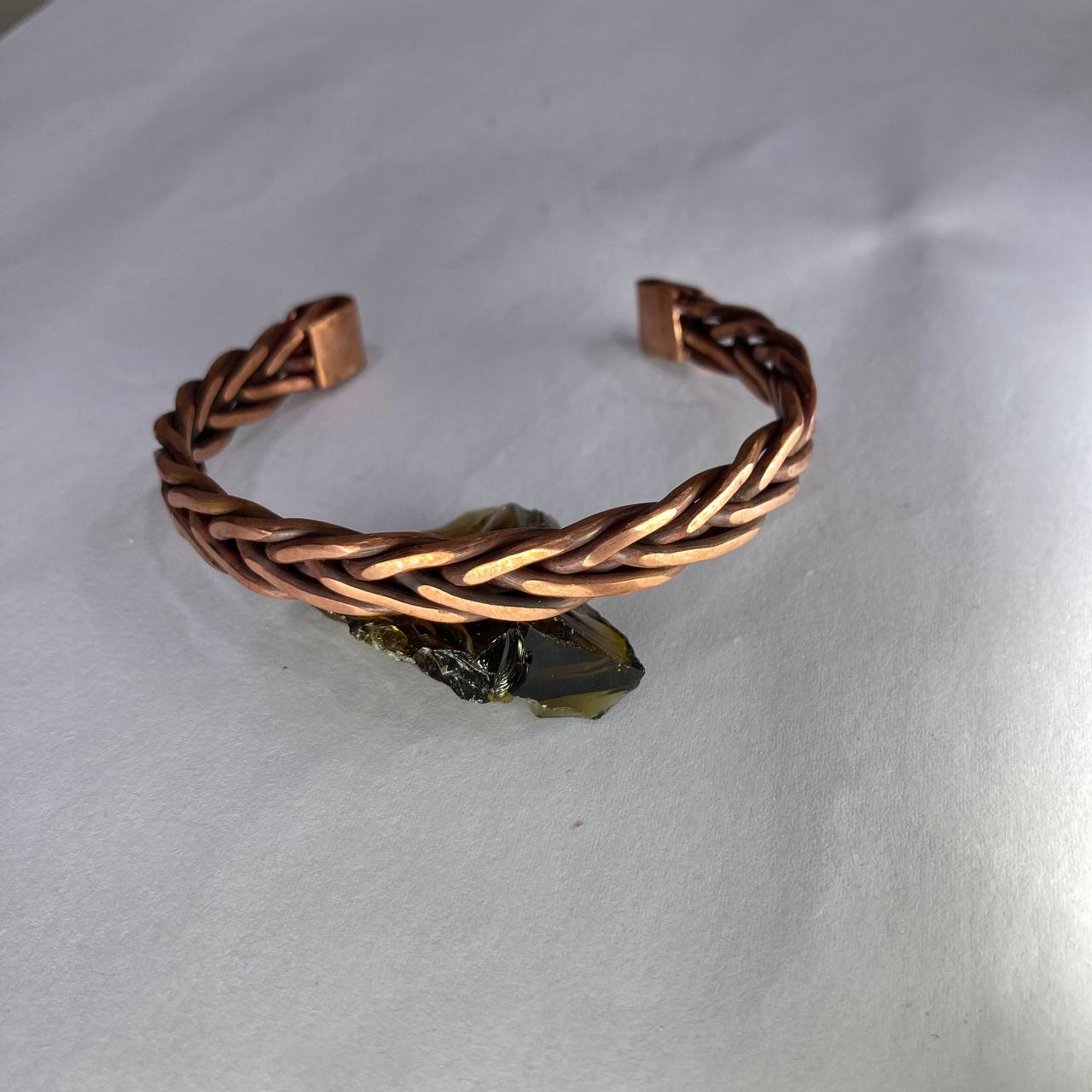 Copper braided bracelet on a light gray background