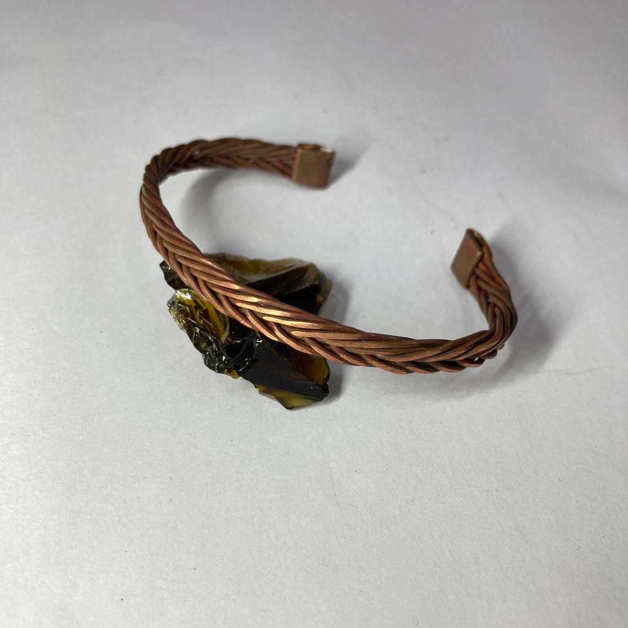 Copper bracelet with embedded stones on a white background