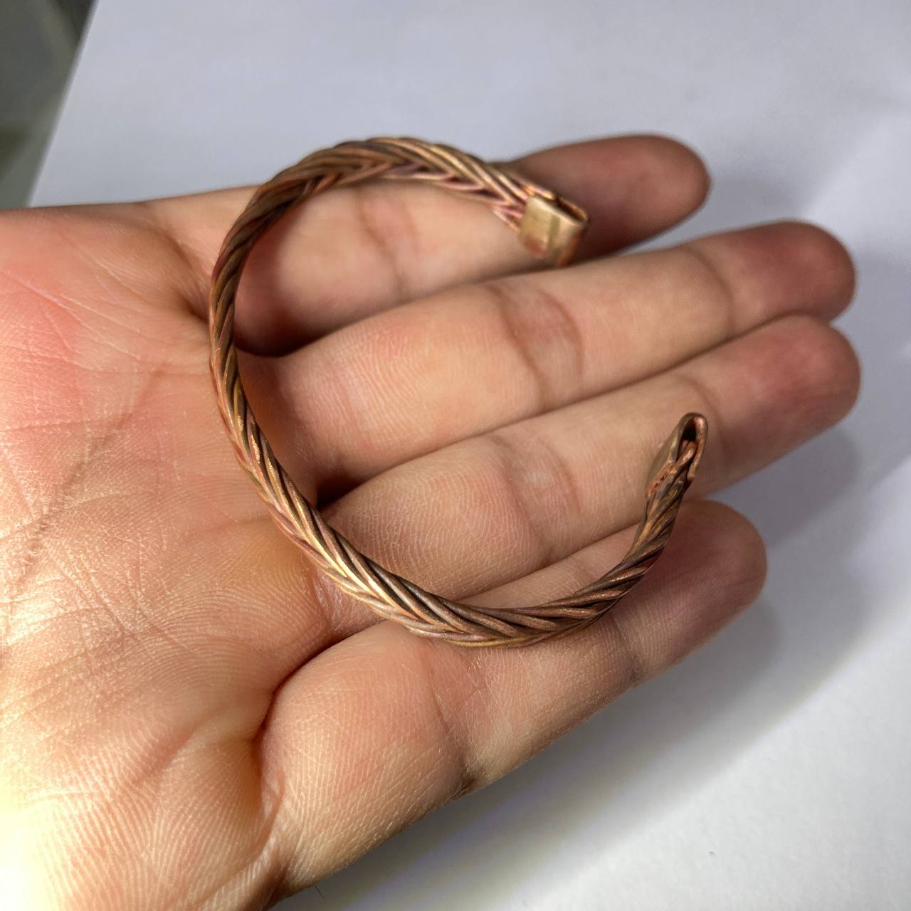 Hand wearing a large copper ring on a white background