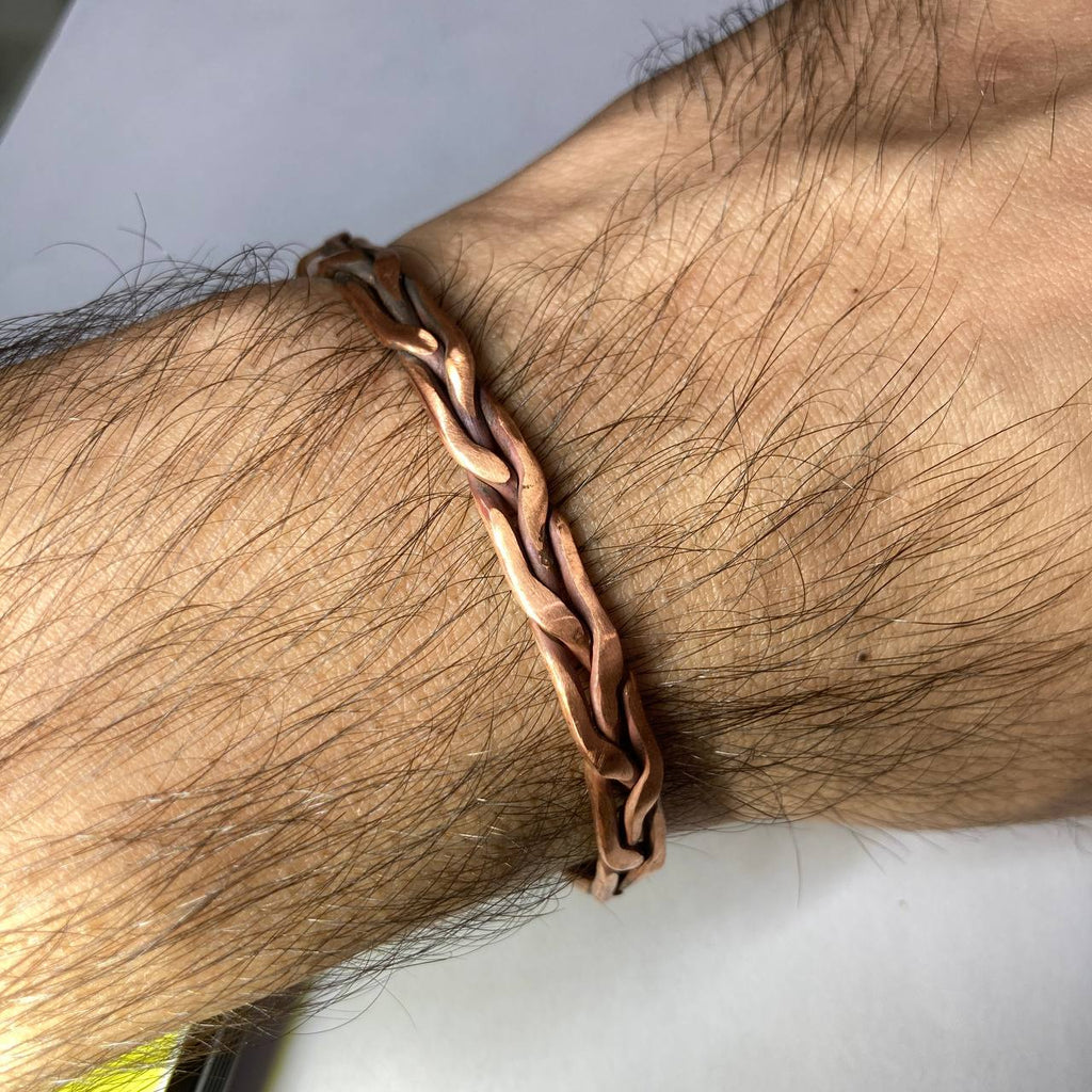 Copper bracelet on a wrist with a neutral background
