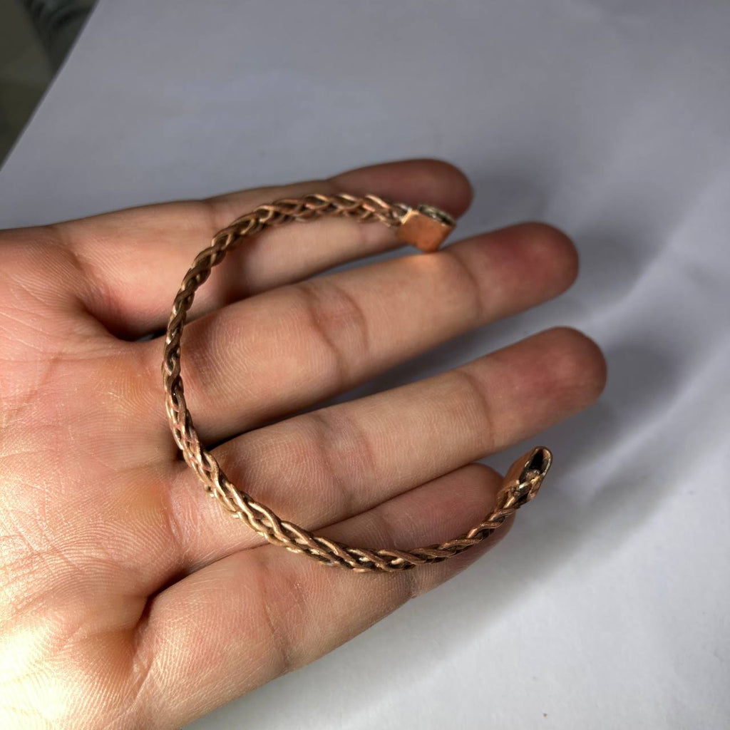 Rose gold chain held in a hand against a white background